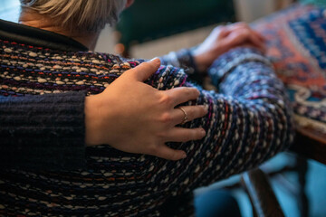 A close-up view of a person's hand gently resting on another person's shoulder, conveying a sense of comfort and support.