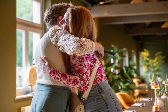 Warm embrace between a man and a woman indoors, conveying a sense of comfort and affection.