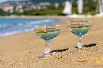 Summer time on French Riviera, two coupe glasses of champagne cremant sparkling wine on Pampelonne sandy beach near Saint-Tropez in sunny day, Var, vacation in France