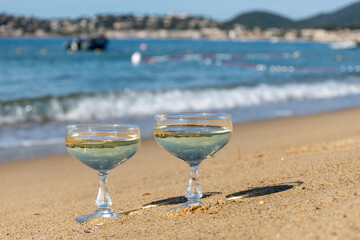 Summer time on French Riviera, two coupe glasses of champagne cremant sparkling wine on Pampelonne sandy beach near Saint-Tropez in sunny day, Var, vacation in France