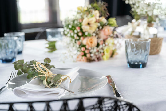 Elegant table setting with white linen, floral arrangements, and a silverware at an upscale event.