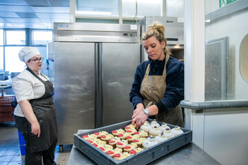 Two chefs decorating pastries in a commercial kitchen.