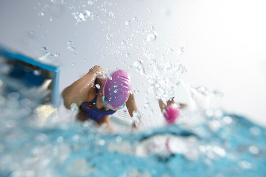 Underwater view of a swimmer in goggles and a swim cap powering through the water with a strong freestyle stroke.