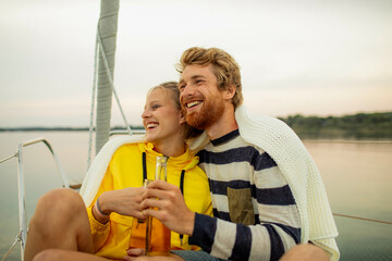 Smiling couple enjoying a moment together on a sailboat at dusk