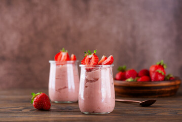 Tofu soy dessert with strawberry in a glass on a brown wooden table. Vegan homemade breakfast.