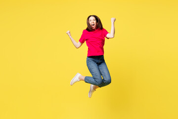 Fototapeta premium Full body young happy woman she wear pink t-shirt casual clothes jump high doing winner gesture celebrate clenching fists isolated on plain yellow orange background studio portrait. Lifestyle concept.