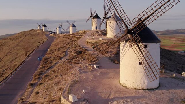 Aerial view of traditional windmills, castle, and road at sunrise, Consuegra, Toledo, Spain.