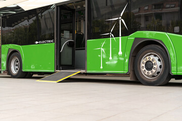 Green coloured electric bus powered by renewable energy with logos of wind turbines.