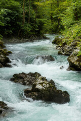 Fototapeta premium Vintgar Gorges Park a few km from Lake Bled, Slovenia. Wooden walkways accompany the path above the river rapids and waterfalls. River hits rocks and creates fog.Adventure family holidays. Freshness.