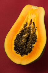 Half of a juicy ripe papaya on a burgundy background