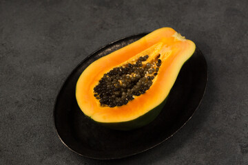 Half of a juicy ripe papaya on a metal plate