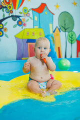 A baby learns to swim with a coach in the pool. Swimming courses for small children. Baby boy swims in the pool.