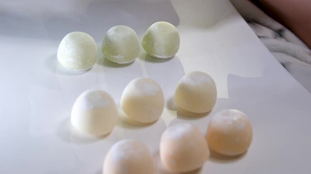 Photos of motti of different colors with different fillings isolated on white background, a delicious colored dessert.