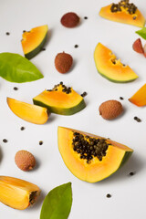 Fruit background made of pieces of ripe papaya, persimmon and litchi on a white background