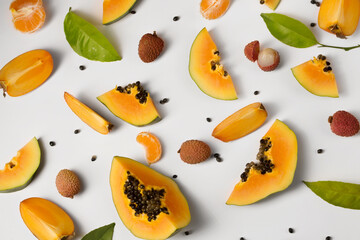 Fruit background made of pieces of ripe papaya, persimmon and tangerine on a white background