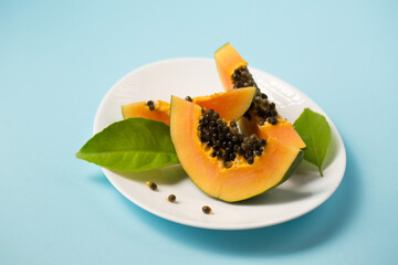 Ripe papaya in a white plate on a blue background