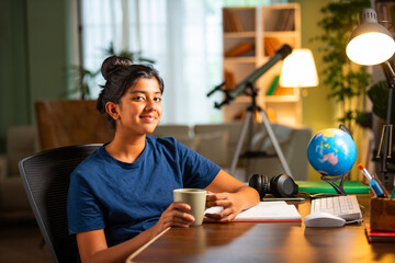 Asian Indian small girl takes break from study drink milk in cup