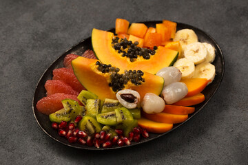 A large plate with sliced ​​tropical fruits on a metal vintage plate