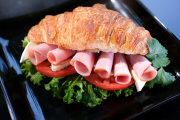 Croissant with meat. Zoom-in close up view of breakfast meal: croissant sandwich with bacon and...