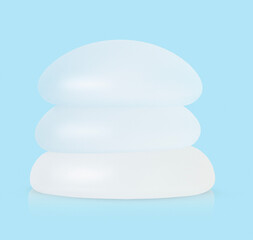 Stack of different types of breast implants on blue background.