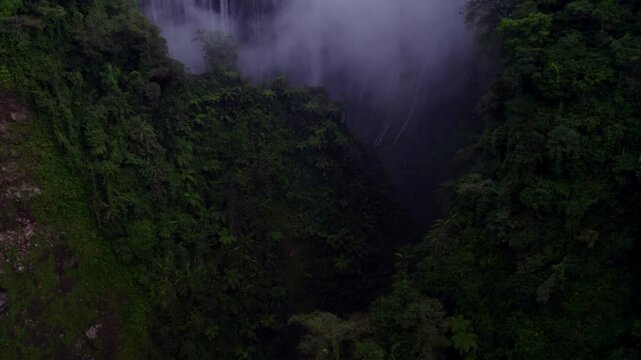 Aerial view of lush waterfall and steamy jungle with majestic volcano Semeru, Tumpak Sewu, East Java, Indonesia.