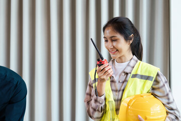 Female Engineer Communicating with Walkie-Talkie and Holding Safety Helmet at Construction Site