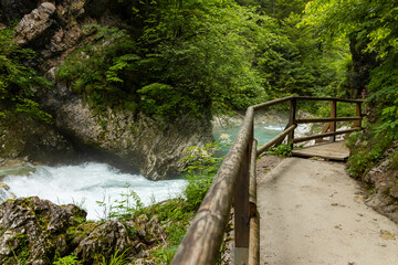 Vintgar Gorges Park a few km from Lake Bled, Slovenia. Wooden walkways accompany the path above the river rapids and waterfalls. River hits rocks and creates fog.Adventure family holidays. Freshness.