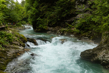Vintgar Gorges Park a few km from Lake Bled, Slovenia. Wooden walkways accompany the path above the river rapids and waterfalls. River hits rocks and creates fog.Adventure family holidays. Freshness.