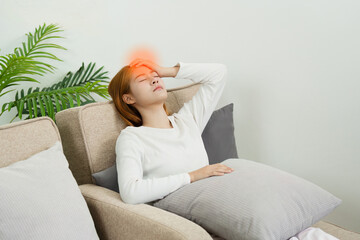 young asian woman have fever and head ache sitting on a couch in the living room at home