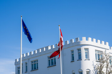 Flag of the European Union and the Danish flag against a blue sky in front of the Danish embassy in Reykjavik, Iceland, waving in the wind, lots of copy space