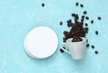 Coasters with coffee beans in cup, white round mockups on blue concrete background