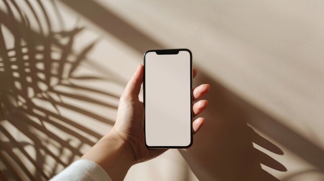 a studio photo of a hand holding an iphone with green screen, A beige seamless background with a sunlight feel. Dramatic lighting,
