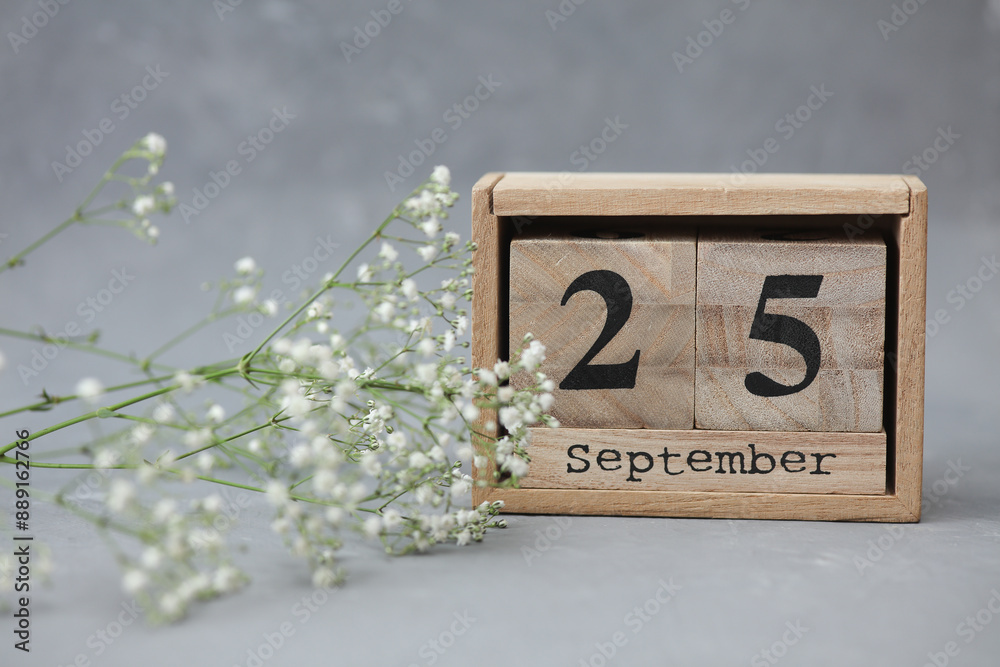 Poster wooden calendar with the date september 25 and gypsophila flowers on a gray concrete background