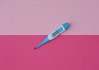 Electronic thermometer on pink background. Top view