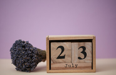 Wooden block calendar with the date July 23 and a bouquet of dry lavender flowers