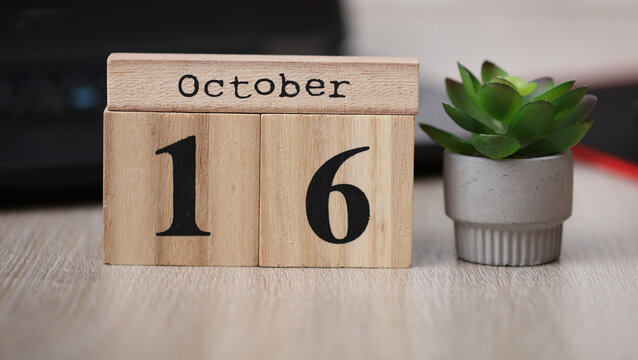 Wooden calendar with the date October 16 on desktop with laptop