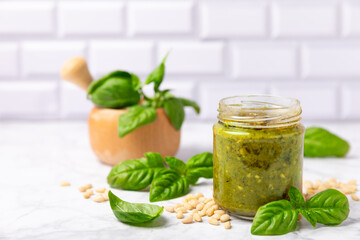 Pesto. Italian basil pesto sauce on a textured wooden background. Ingredient for pesto sauce: fresh basil, pine nuts, Parmesan cheese and olive oil. Space for text.Copy space.