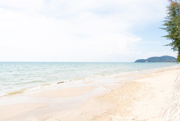 Obraz premium Landscape nature view of beautiful tropical beach and sea in sunny day. White, brown clean beach sea space area blue waters and sunny skies were beautiful. Distant view of mountain of island.