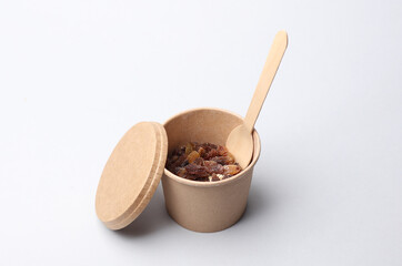 Disposable cardboard box, food container with oatmeal and raisins on a white background.