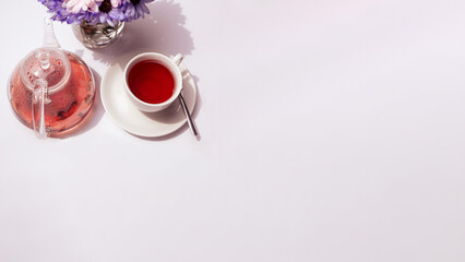 a cup of tea with teaspot and flowers on the white background with a spare space for inscription