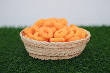 snack cheese crackers in a basket on green grass with white background.