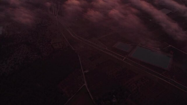 Aerial view of serene sunrise over Ginosa city with misty clouds, Taranto, Italy.
