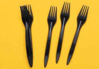 Black plastic forks on a yellow background