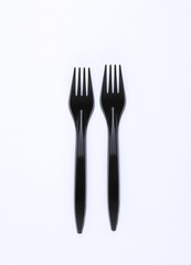 Black plastic forks on a white background
