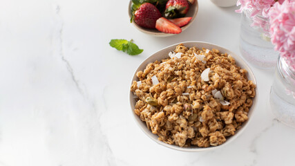 Crispy homemade granola with sliced almonds in a bowl with strawberries. Healthy eating. Copy space