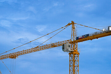 Construction tower crane are working. close up view on blue sky background.