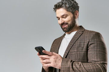 A stylish man in a suit gazes at his cellphone intently, lost in thought.