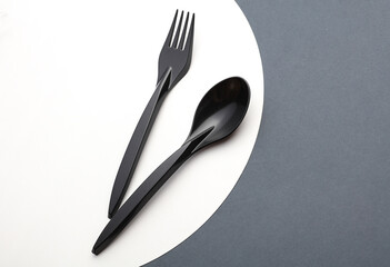 Black plastic spoon and fork on white gray background