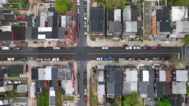 Top-down view of an American urban neighborhood. Grid pattern streets with row houses and parked cars. Dense residential area, aerial shot.