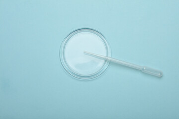 Petri dish with pipette on blue background. Top view